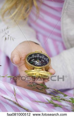 Stock Image - Girl holding compass, cropped. Fotosearch