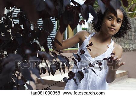 Girl looking from behind leafy branches View Large Photo Image Stock Photo - Girl looking from behind leafy branches. Fotosearch