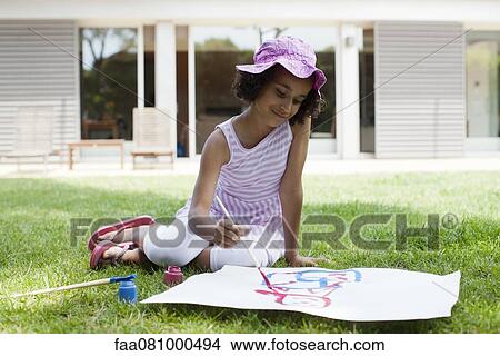 Girl sitting on grass drawing on paper View Large Photo Image Picture - Girl sitting on grass drawing on paper. Fotosearch
