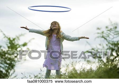 Stock Photography - Girl throwing plastic hoop in air. Fotosearch