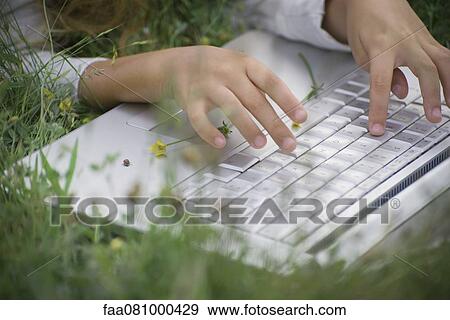 Girl using laptop computer in grass, cropped View Large Photo Image Stock Photo - Girl using laptop computer in grass, cropped. Fotosearch