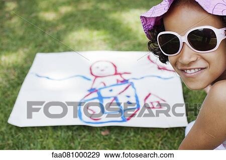 Stock Photo - Girl with drawing on grass. Fotosearch