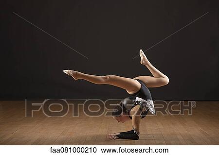 Stock Image - Gymnast bending backwards, balancing ball with head. Fotosearch