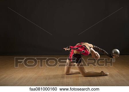 Stock Image - Gymnast bending backwards holding ball. Fotosearch