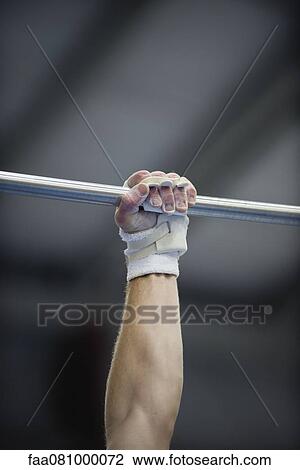 Stock Image - Gymnast's arm holding onto horizontal bar, cropped. Fotosearch