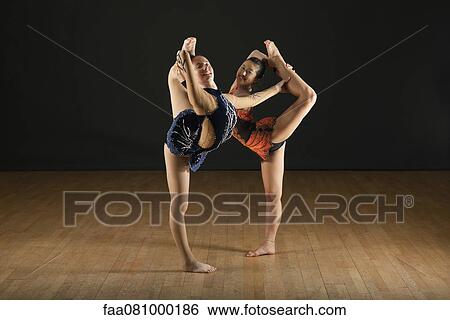 Stock Photograph - Gymnasts performing standing splits together, portrait. Fotosearch
