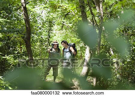 Stock Image - Hikers looking at map in forest. Fotosearch