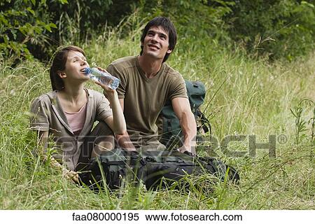 Stock Photography - Hiking couple relaxing in meadow. Fotosearch