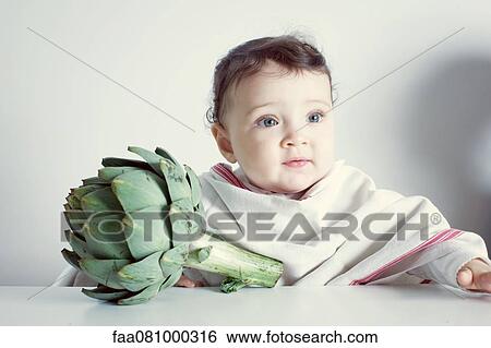 Stock Photograph - Infant and fresh artichoke, portrait. Fotosearch