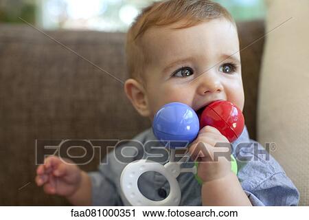 Stock Image - Infant chewing on rattle. Fotosearch