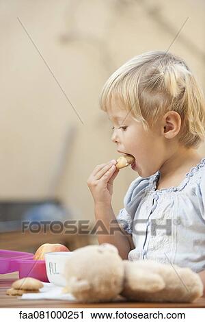 Stock Image - Little girl eating cookies. Fotosearch
