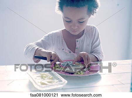 Stock Image - Little girl preparing a snack. Fotosearch