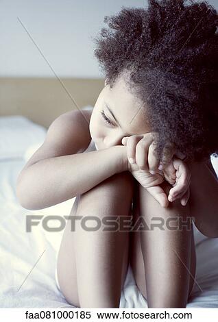 Stock Photography - Little girl resting head on knees, portrait. Fotosearch