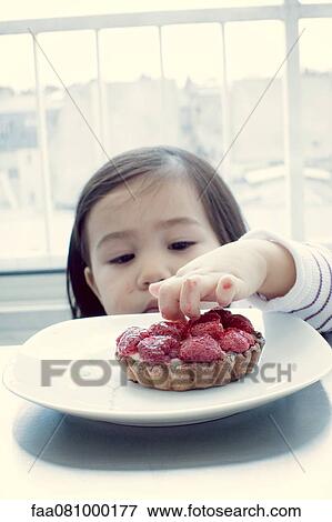 Stock Photo - Little girl sticking fingers in fruit tart. Fotosearch