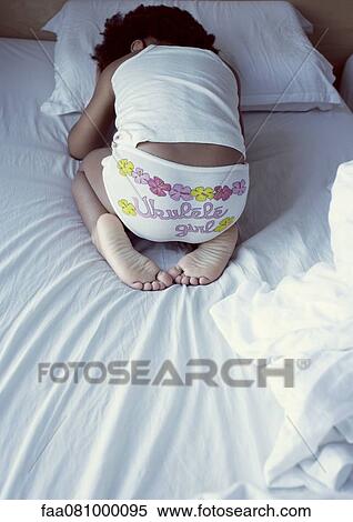 Stock Photography - Little girl waking up in morning, rear view. Fotosearch