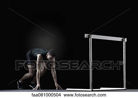 Picture - Male athlete at starting position in front of hurdle. Fotosearch