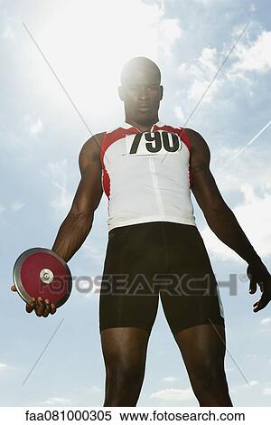 Stock Photography - Male athlete holding discus, low angle view. Fotosearch