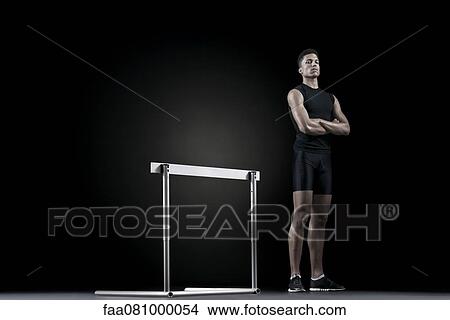 Male athlete standing by hurdle View Large Photo Image Picture - Male athlete standing by hurdle. Fotosearch