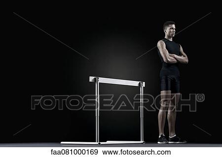 Stock Photo - Male athlete standing by hurdle. Fotosearch