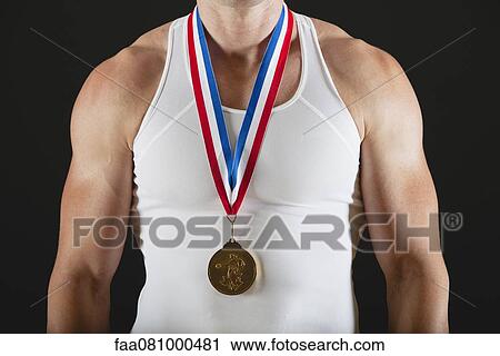Stock Image - Male gymnast with gold medal, mid section. Fotosearch