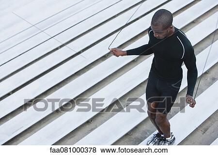 Stock Photo - Man jumping rope on bleacher, high angle view. Fotosearch