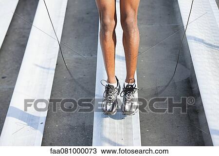 Stock Image - Man jumping rope on bleacher, low section. Fotosearch