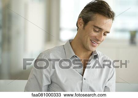 Stock Image - Man looking down and smiling, portrait. Fotosearch
