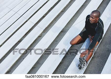 Stock Photo - Man stretching on bleacher, high angle view. Fotosearch