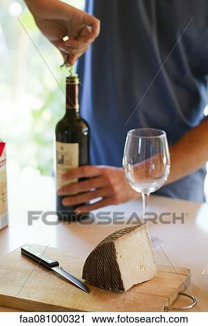 Stock Image - Man uncorking wine bottle, cropped. Fotosearch