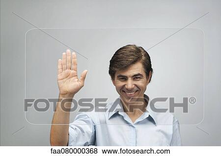 Stock Photo - Man using large transparent touch screen to authenticate his handprint. Fotosearch