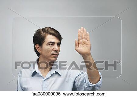Stock Photograph - Man using large transparent touch screen to authenticate his handprint. Fotosearch