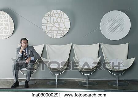 Mature businessman sitting at end of row of chairs in waiting room View Large Photo Image Stock Image - Mature businessman sitting at end of row of chairs in waiting room. Fotosearch