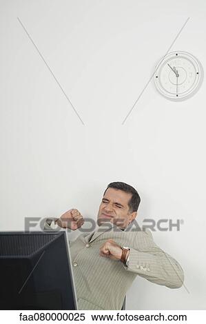 Stock Photography - Mature businessman stretching at desk. Fotosearch