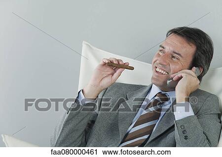 Mature businessman using cell phone and smoking cigar View Large Photo Image Stock Image - Mature businessman using cell phone and smoking cigar. Fotosearch