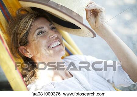Stock Photograph - Mature woman relaxing in hammock, portrait. Fotosearch