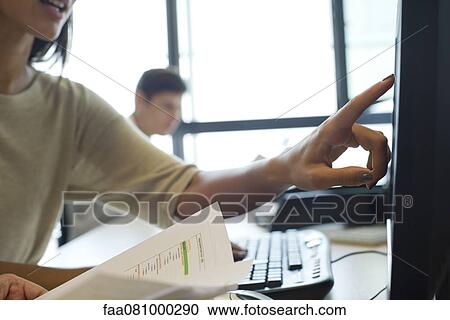 Stock Image - Office worker pointing to computer screen, cropped. Fotosearch