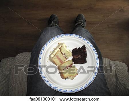 Stock Image - Plate of cake slices on man's lap, directly above. Fotosearch