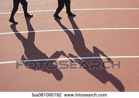 Stock Image - Shadow of men passing baton on running track. Fotosearch
