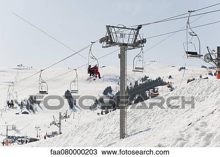 Skiers riding on ski lift at ski resort View Large Photo Image Stock Image - Skiers riding on ski lift at ski resort. Fotosearch