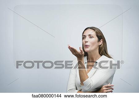 Woman blowing a kiss at large transparent screen View Large Photo Image Picture - Woman blowing a kiss at large transparent screen. Fotosearch