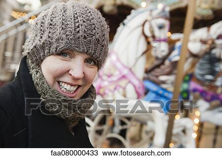Stock Image - Woman in front of carousel, smiling, portrait. Fotosearch