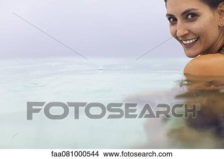 Picture - Woman in water, looking over shoulder at camera, portrait. Fotosearch
