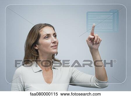 Stock Photography - Woman looking at her schedule of the day on advanced touch screen interface. Fotosearch