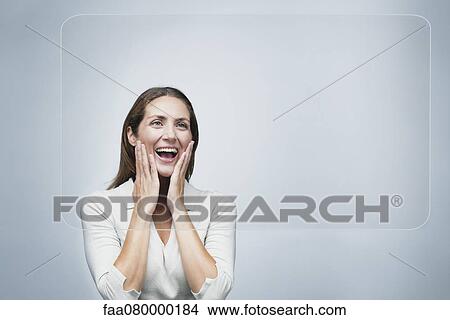 Picture - Woman looking at large transparent touch screen with surprised expression on face. Fotosearch