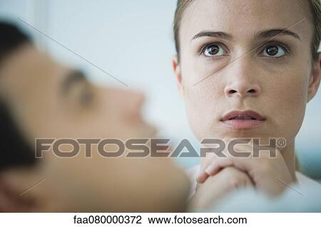 Stock Image - Woman praying, sick man in foreground. Fotosearch