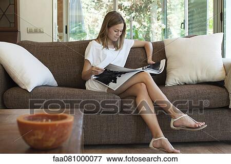 Woman relaxing on sofa with magazine View Large Photo Image Stock Photo - Woman relaxing on sofa with magazine. Fotosearch