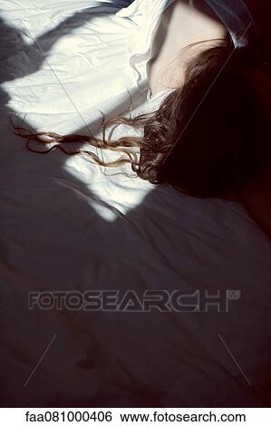 Stock Photograph - Woman resting on bed, cropped. Fotosearch