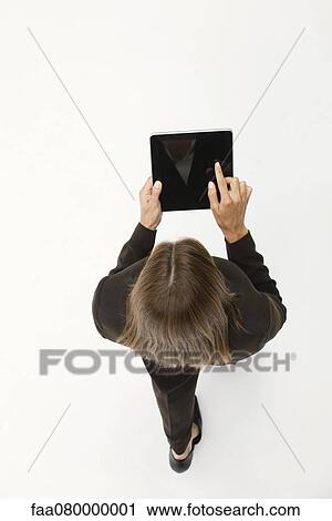 Stock Image - Woman using digital tablet while walking, overhead view. Fotosearch