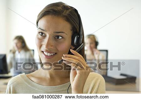 Stock Photo - Woman using headset in office. Fotosearch