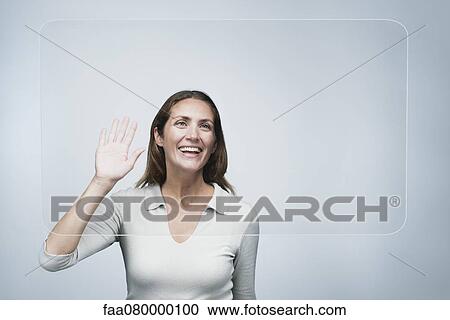 Stock Image - Woman waving at large transparent screen. Fotosearch